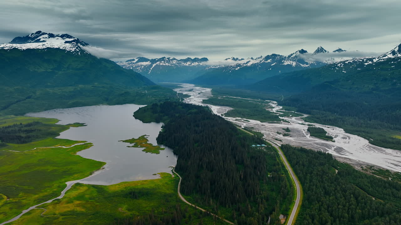Alaska vast, majestic wilderness. Discover Alaska stunning wilderness with its mountains, rivers, and greenery beneath an overcast sky