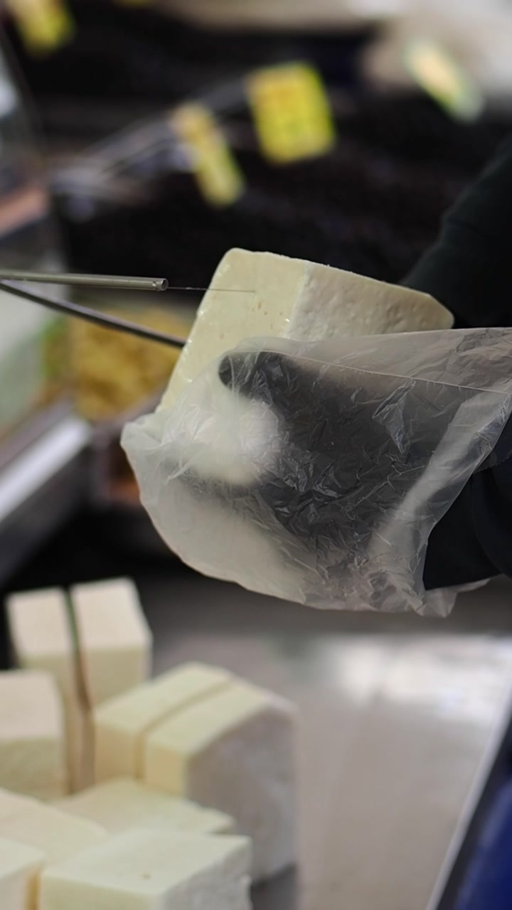 Close-up of a Hand Cutting a Block of Cheese with a Wire