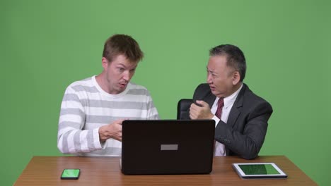 mature japanese businessman and young scandinavian businessman working together