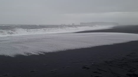 Olas-Del-Mar-Agitadas-Rompiendo-En-Reynisfjara,-Playa-De-Arena-Negra,-Costa-De-Islandia-En-Un-Día-Frío-Y-Lluvioso