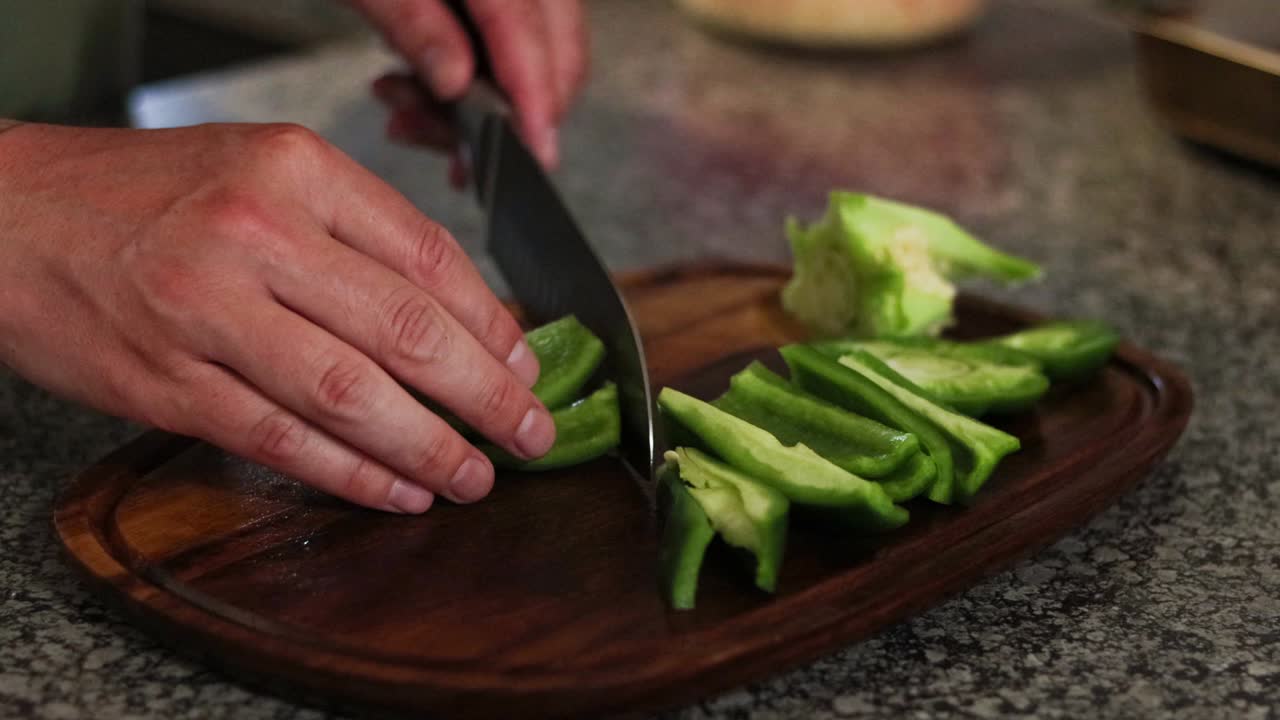 picar un pimiento verde en una tabla de cortar de madera