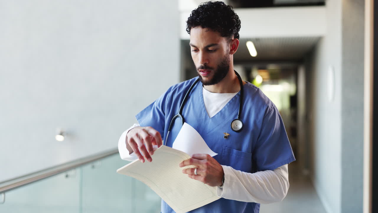 Male Medical Professional Examining Patient Files in Hospital Hallway