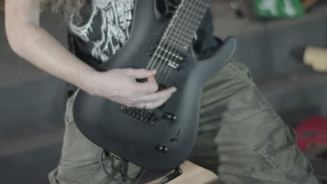 guitarist playing on a black seven string guitar in an upright position