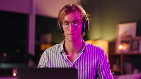 man with headphones using laptop at night