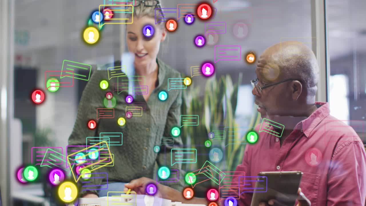 Seated man tapping tablet, woman pointing model with pencil, activating chat overlay for design