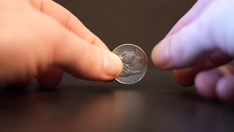 a man spins a quarter in slow motion, slightly in and out of focus