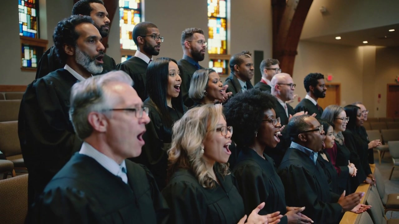 Iniziando con i movimenti della bocca, coro della chiesa che canta e applaude nel santuario, indossando tuniche nere.