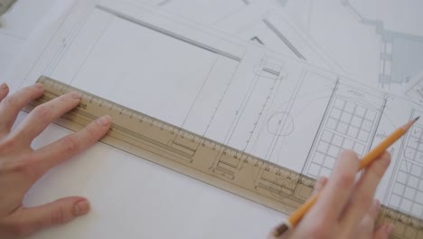 hands meticulously working on an architectural drawing, using a ruler and pencil to ensure precision in the design of a building or space, reflecting the detailed nature of architectural planning