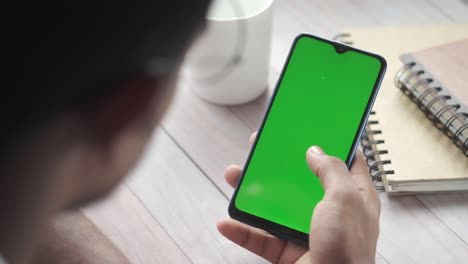 person using a smartphone with a green screen