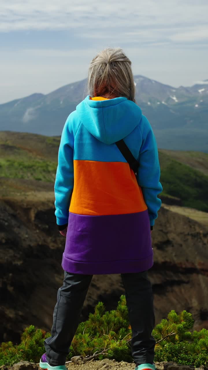 Vrouw staat op bergtop en kijkt uit over schilderachtig landschap