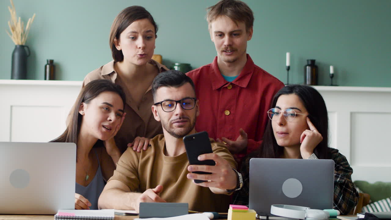 vista frontal del grupo de estudio haciendo un selfie sentado en la mesa con computadoras portátiles y portátiles