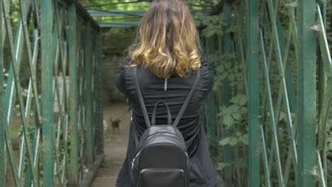girl arranging her hair and hanging onto bridge in the park