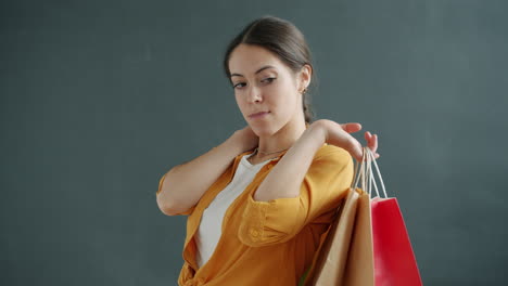 woman holding shopping bags with an unhappy expression