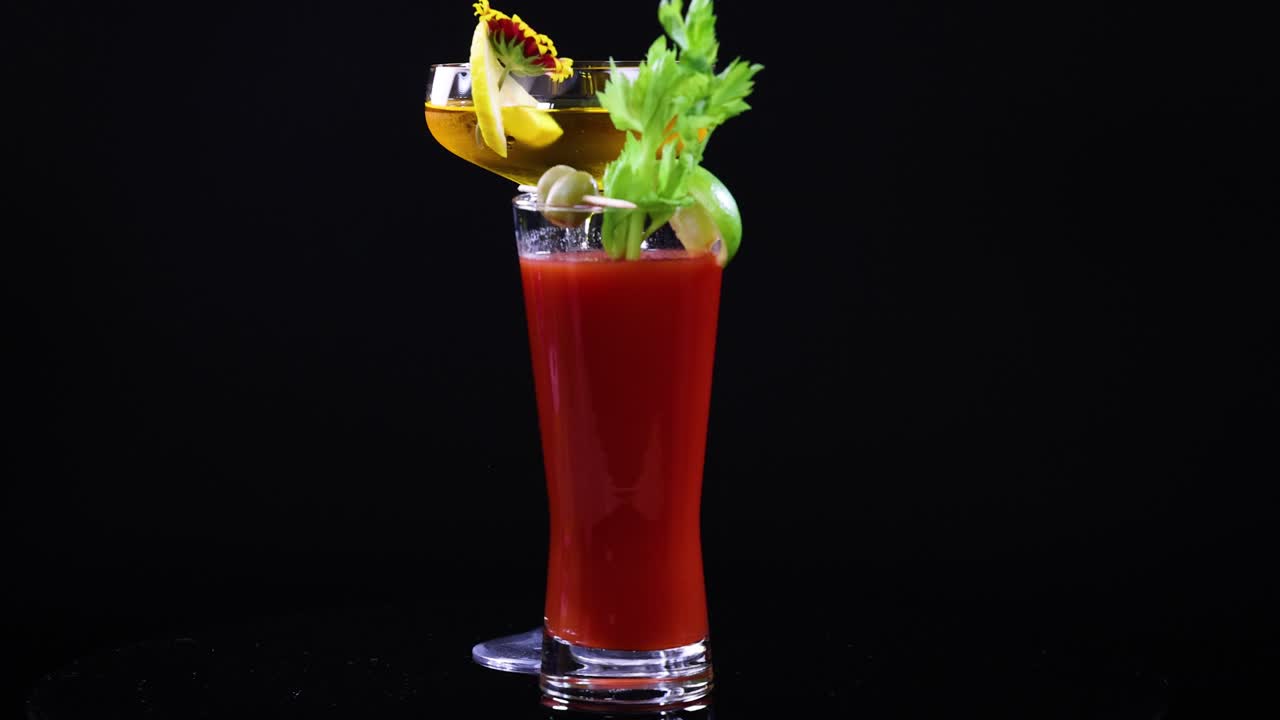 Two colorful cocktails with garnishes set against a black background, highlighting vibrant colors and elegant glassware