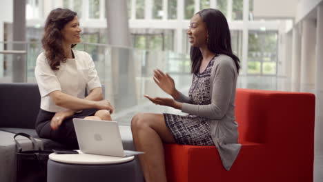 two businesswomen working in lobby of modern office