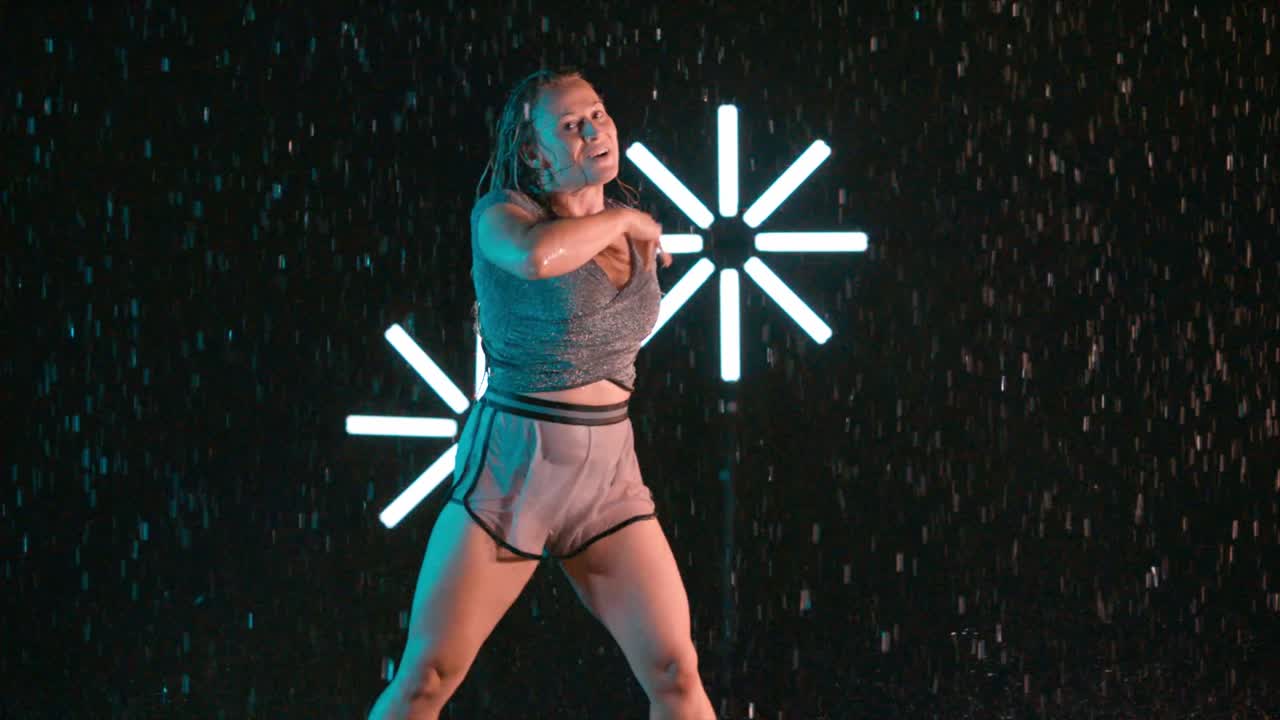 Beautiful female dancing in the rain, modern hip hop performance, indoor rain effect