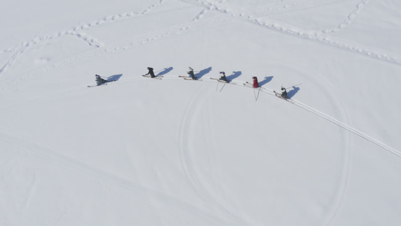 Tuva men in traditional clothing and fur skis walking in snow. Hemu Village, Xinjiang, China. Epic top down aerial view