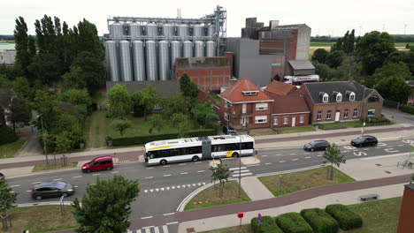 Busy-city-street-with-massive-silos-in-background,-aerial-view