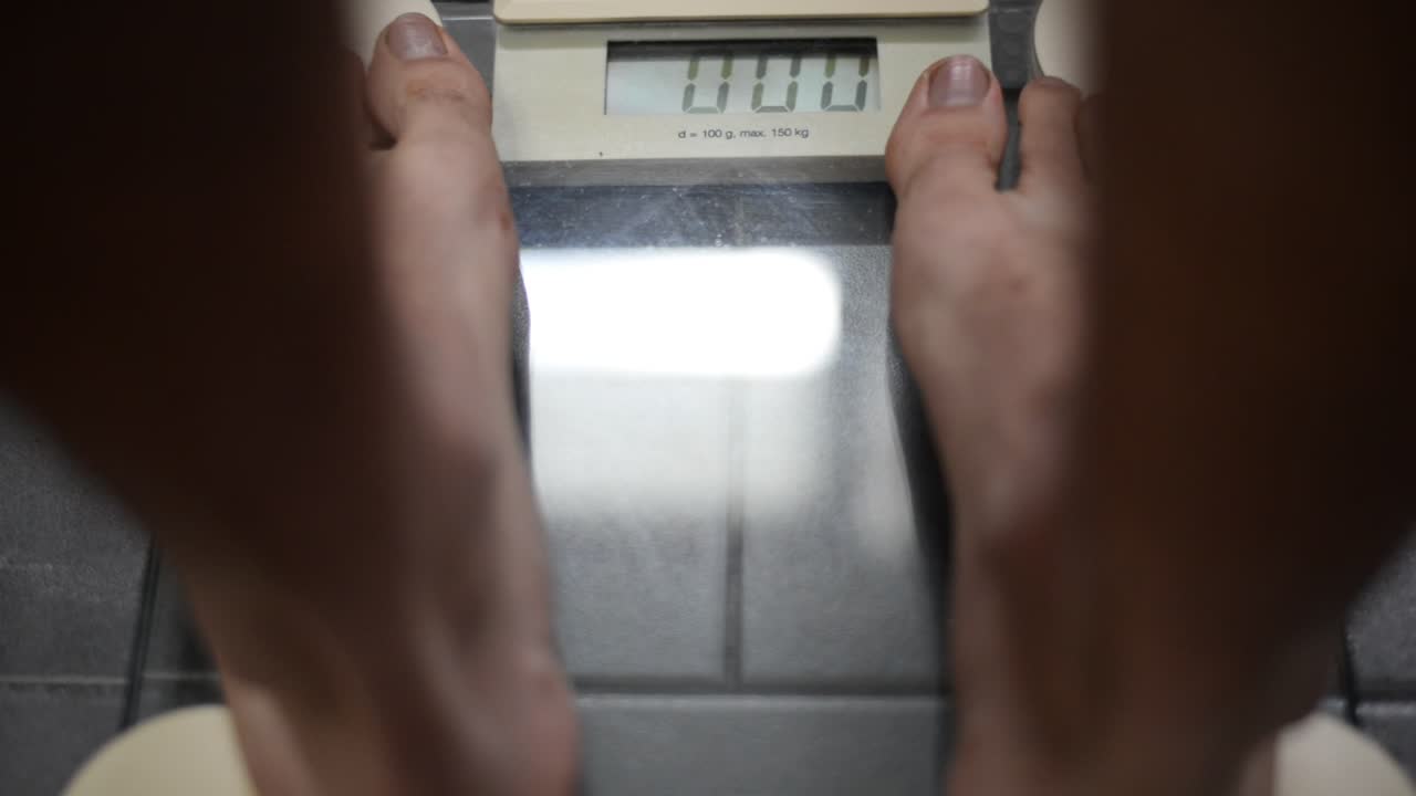 회색 타일에 있는 디지털 욕실 저울을 밟고 있는 발 가까이