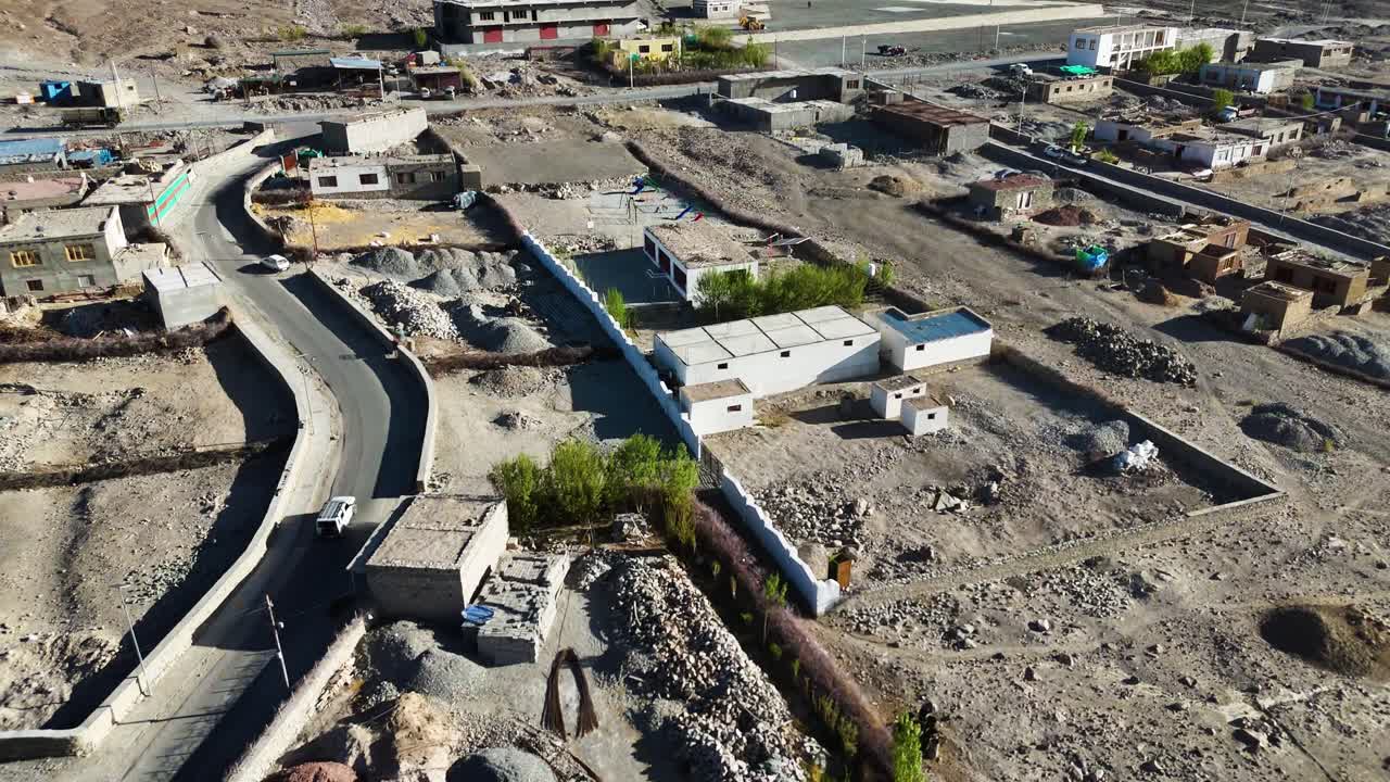Aerial drone shot showcasing a vehicle navigating the remote, rugged terrain of Ladakh.