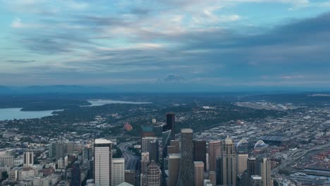 wide aerial view of seattle's skyscrapers reaching up to the clouds and mount rainier hidden in the distance