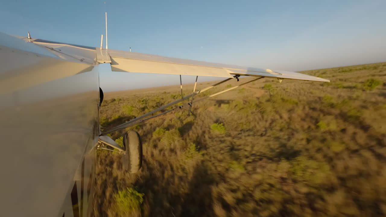 Kleines Flugzeug von der Seite über einer trockenen Gras-Savanne.