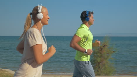 couple in headphones jogging along the sea front