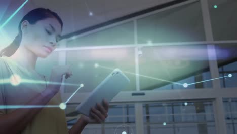 Animation-of-connected-dots-moving-over-asian-businesswoman-using-digital-tablet-in-office