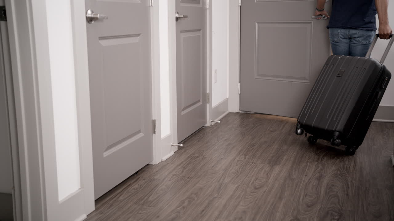 un hombre con un equipaje rodante saliendo de su apartamento