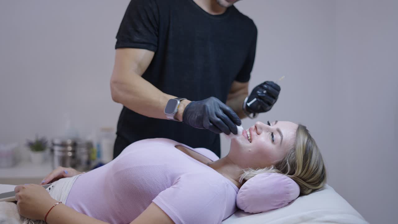 Woman receives cosmetic lip treatment from a professional