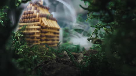 escena en miniatura con un pequeño edificio en humo en madera de primavera