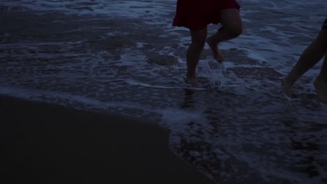 anonymous couple running on evening beach