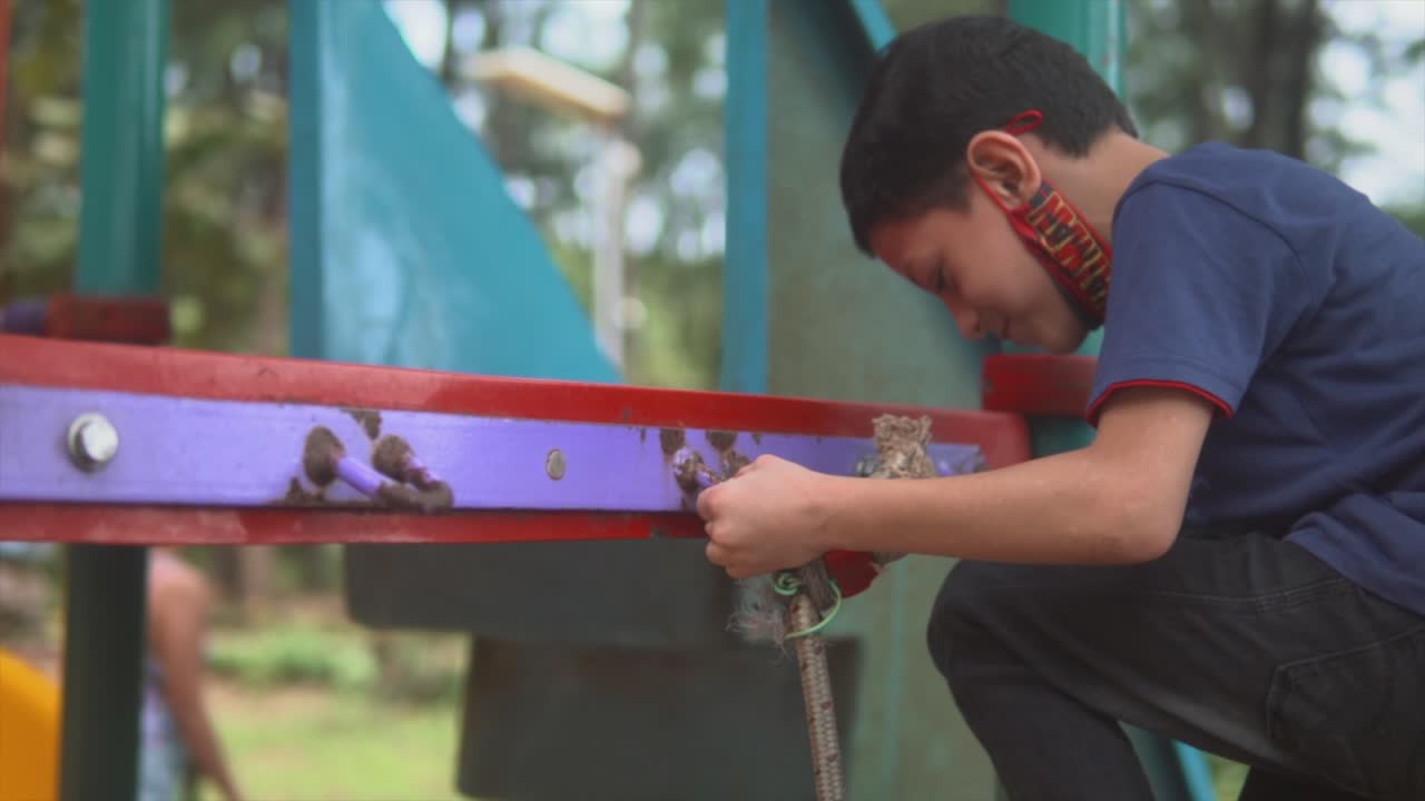 Happy kid climbing the rope at the colourful playground