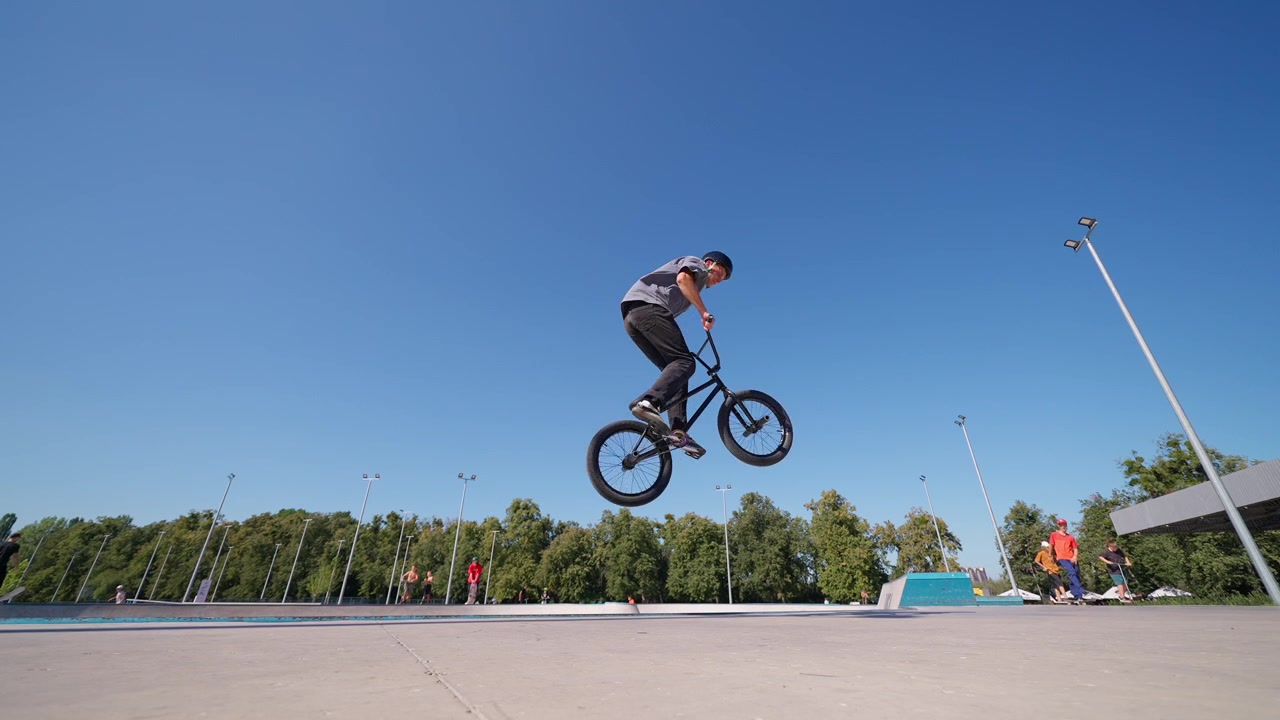 Giovane uomo in BMX che salta in alto in uno skatepark all'aperto