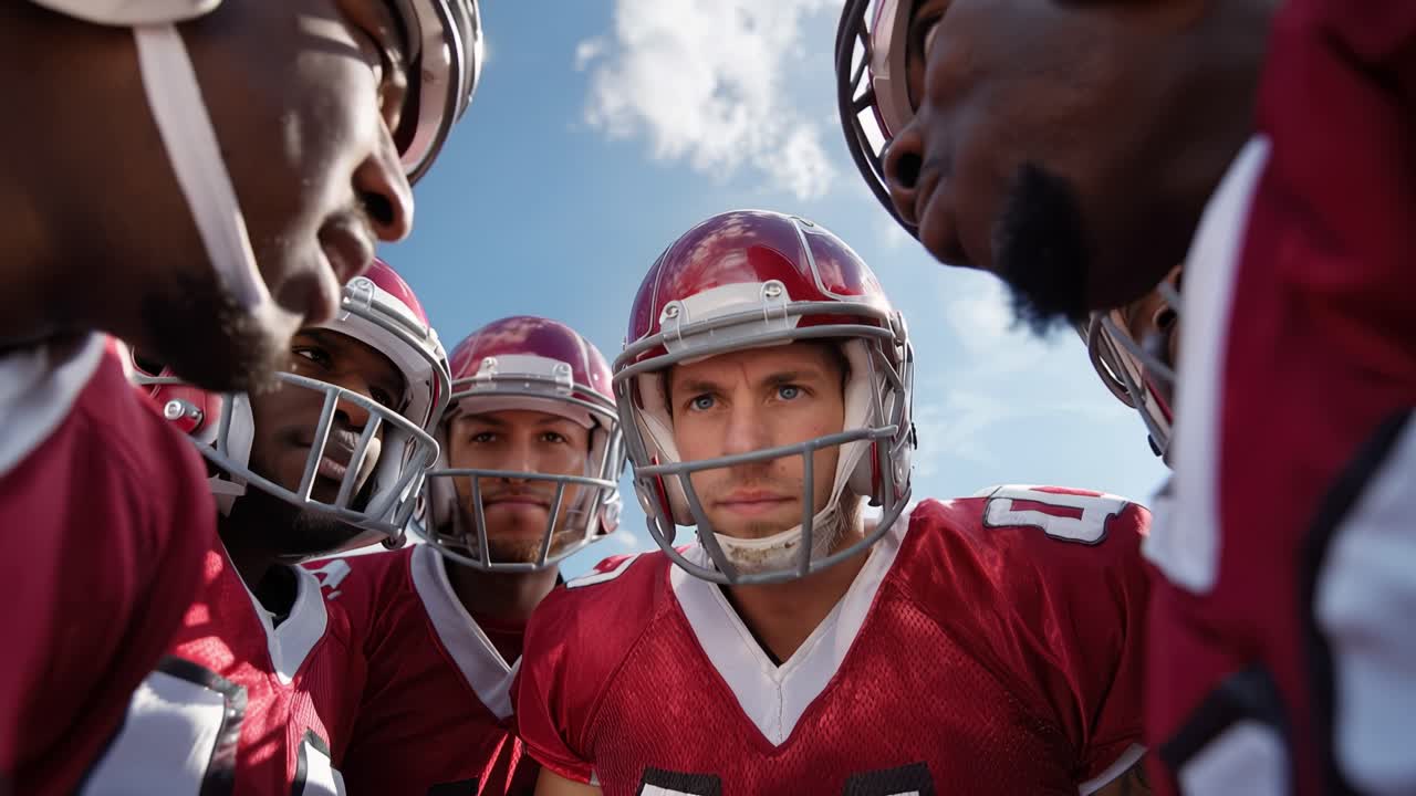 I giocatori si stringono, concentrati e seri. La luce del sole brilla sui caschi, proiettando ombre. I legami di squadra si formano attraverso una tranquilla intensità. Ideale per sport, unità di squadra o immagini motivazionali.