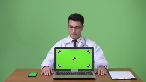 joven hombre hispano guapo médico contra fondo verde