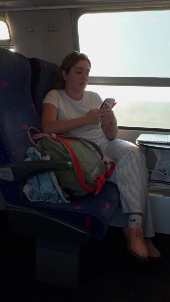 Relaxed Female Traveler Using Her Phone on a Train Journey