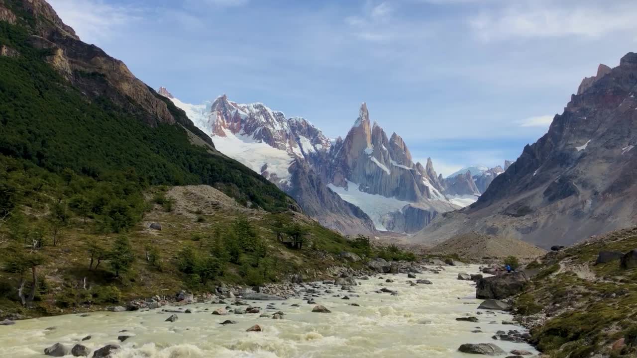 Vallée fluviale en Patagonie avec des montagnes enneigées au loin.