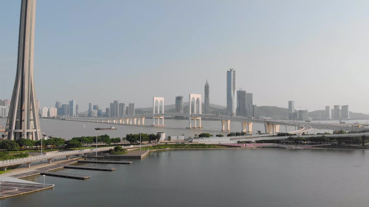 Scatto con drone su treppiede con la base della Torre di Macao in primo piano, il Ponte Sai Van con traffico in secondo piano e la Cina continentale sullo sfondo