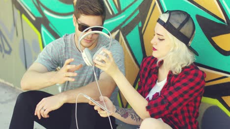 una divertida pareja de jóvenes hipsters escuchando música.