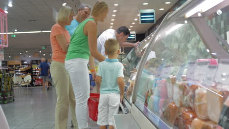 family in front of display refrigerator in supermarket