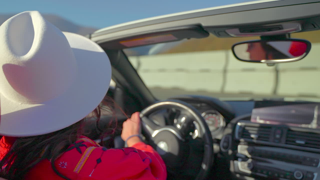 mujer conduciendo un coche convertible en una carretera panorámica