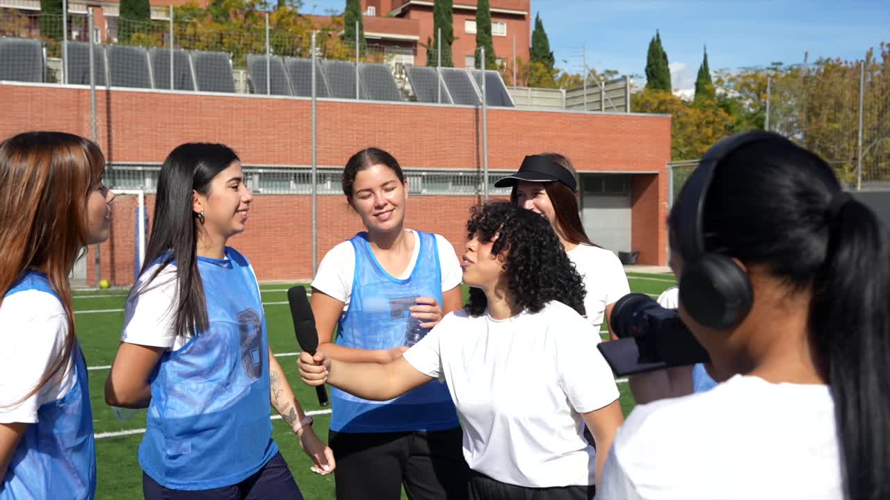 A group of women being interviewed on a sports field