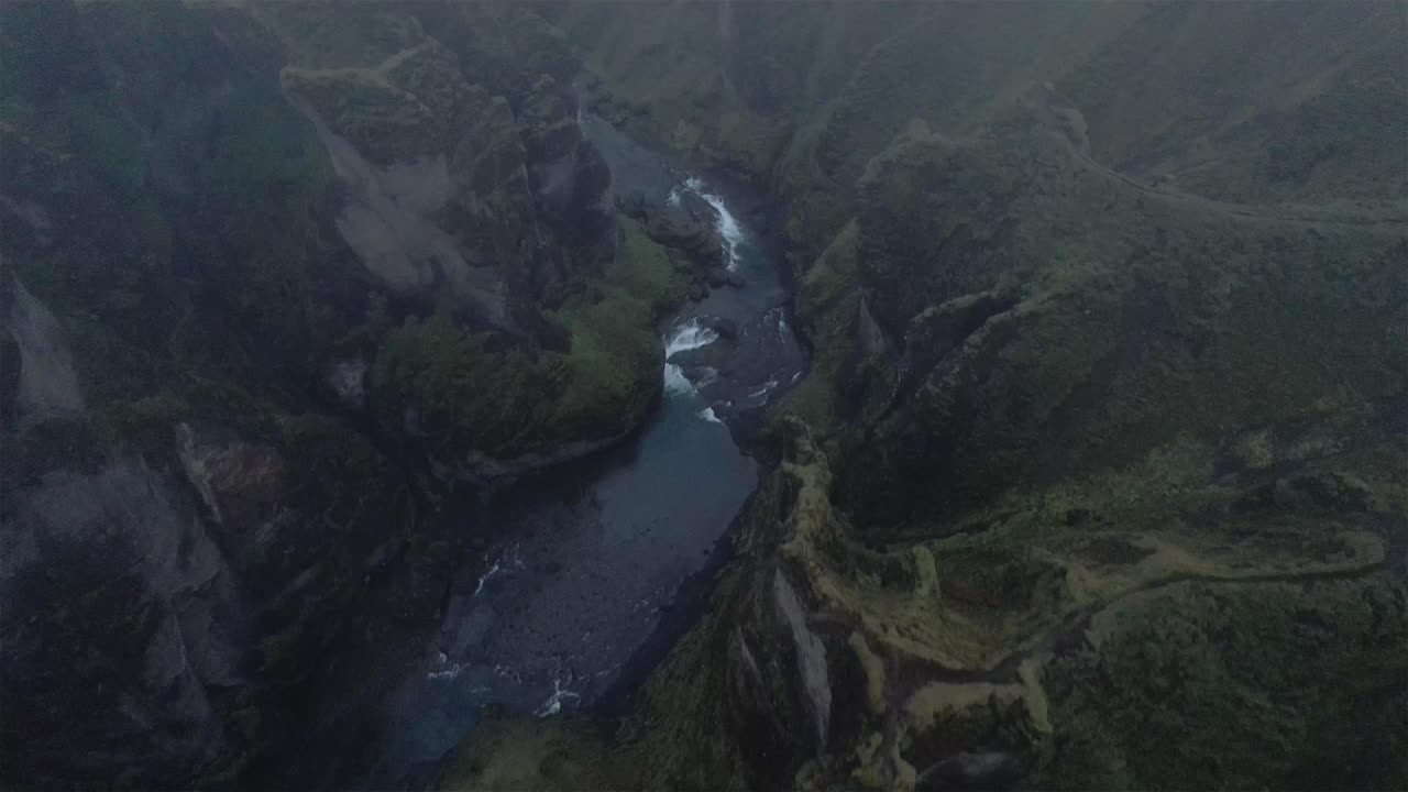 disparo de dron volando sobre el cañón nublado fjaðrárgljúfur con la cámara inclinada hacia abajo en islandia 4k