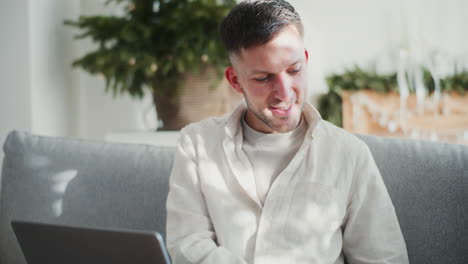 joven empresario sonriente trabaja remotamente desde casa en una computadora portátil