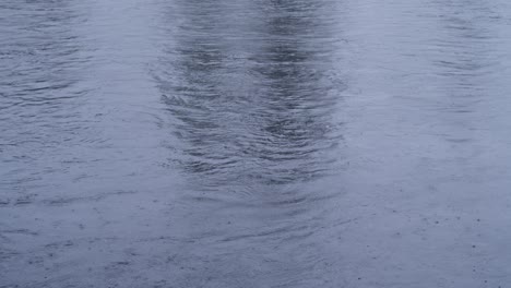 Superficie-Del-Agua-Durante-La-Lluvia-Ligera-Con-Gotas-De-Lluvia-En-Tono-Azul