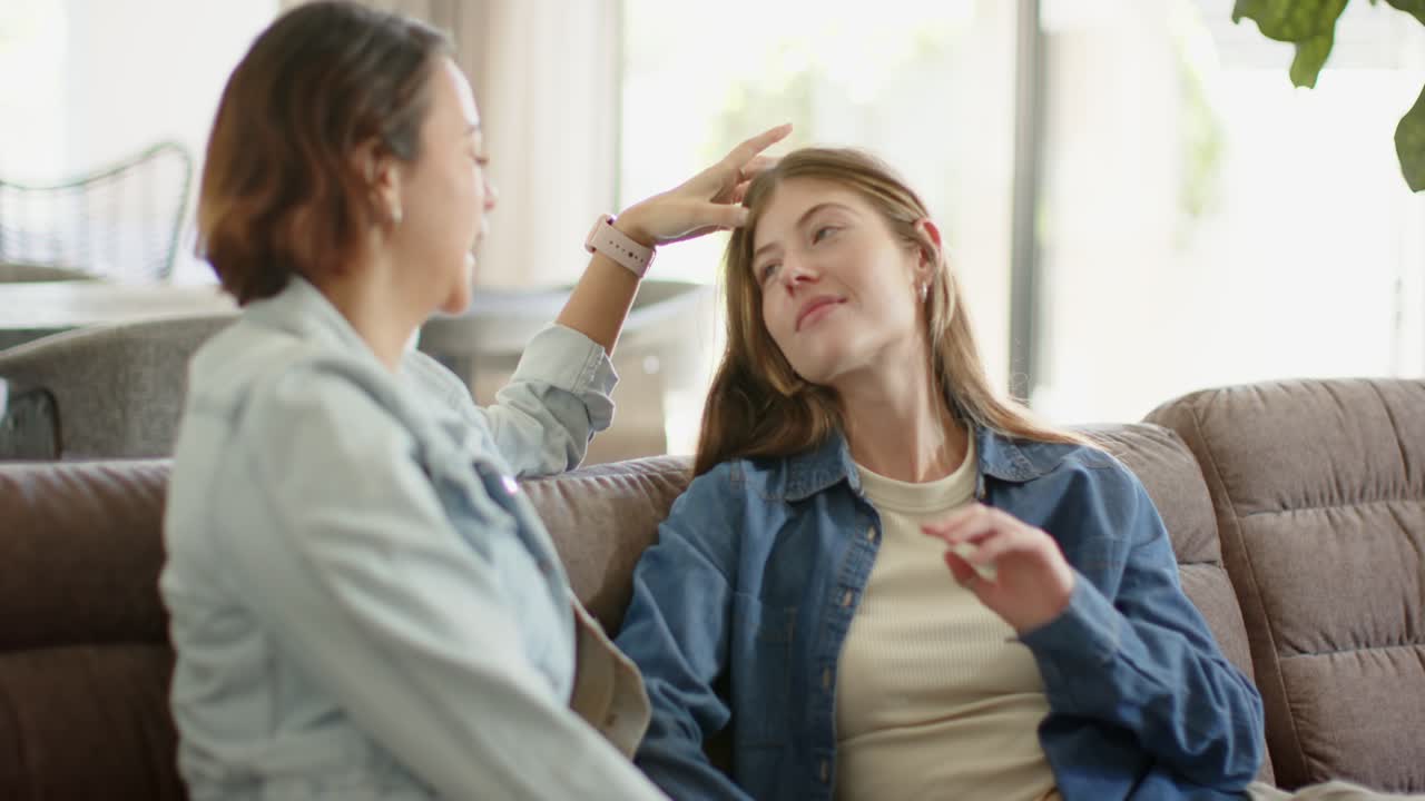 ふざけながらチャットしている時にソファに座っている女性の友人。左の女性は髪に手を伸ばし、右の女性をなだめている。