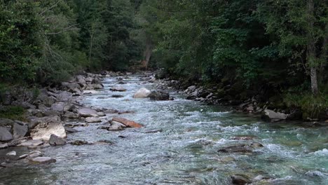 Sereno-Flujo-Del-Río:-Naturaleza-Tranquila-Con-Suave-Caricia-De-Piedra.