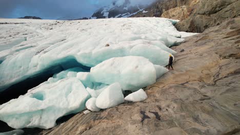 Woman-walking-around-massive-ice-block-and-glacier-in-Alps