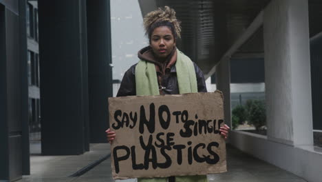 joven activista climático estadounidense sosteniendo un cartel y protestando contra los plásticos de un solo uso mientras mira la cámara 1